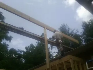 Carpenter setting a ridge beam over a new addition frame — Ice Dam Removal by Roofing Brothers in Arroyo Hondo