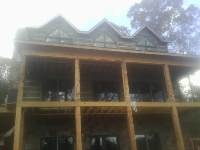 Dormers and porch framing on a large log home under construction — Roof Coating work by our crew in Arroyo Hondo
