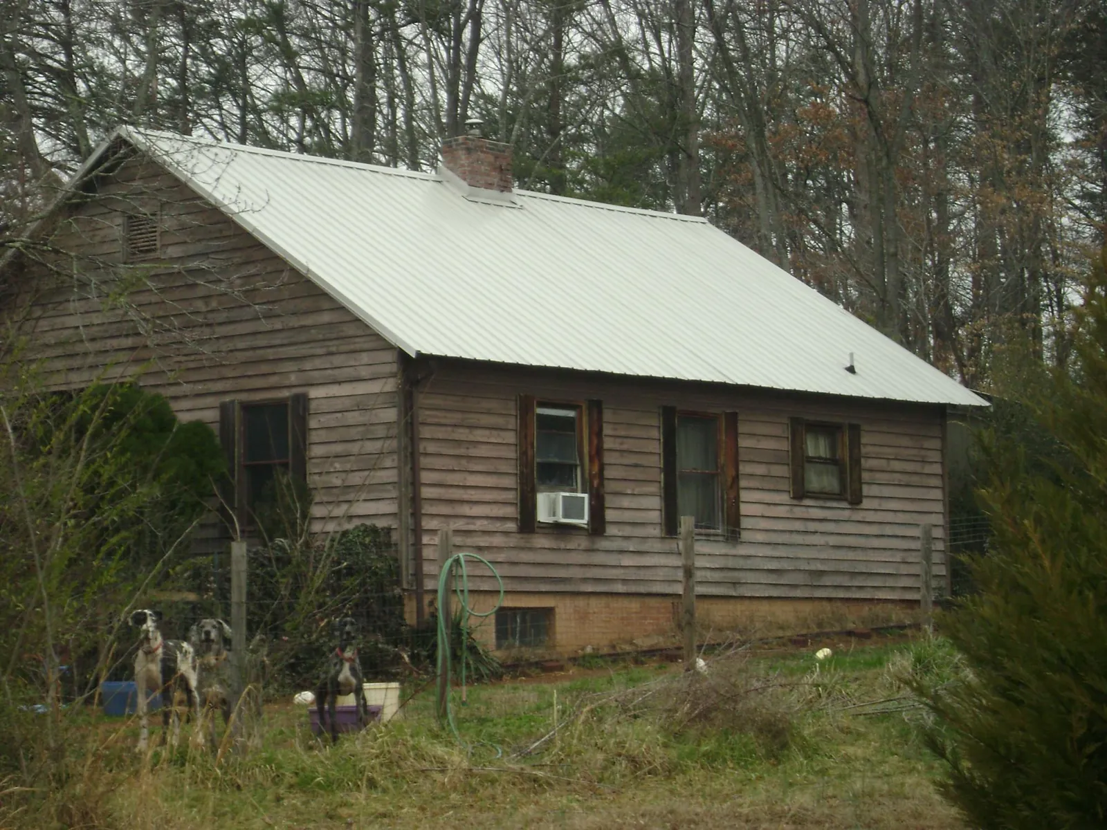 White metal roof on an old wood sided farmhouse, from a Metal Roof Installation job in Arroyo Hondo