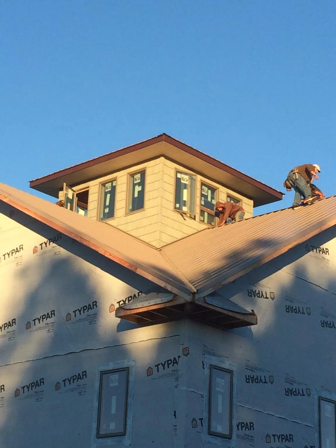 Roofers working around a rooftop cupola on a new metal roof at sunset — Roof Waterproofing in Arroyo Hondo by Roofing Brothers